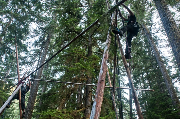 Climbers use DIY lanyards to hold themselves in position while rigging a tri-bi-mono-pod during an Earth First! Climbers Guild camp in Oregon.