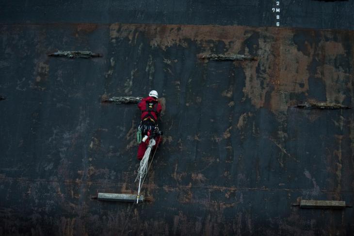 Andreas Widlund aid climbs between sacrificial zinc anodes on the pontoon of the Polar Pioneer oil rig. © Vincenzo Floramo / Greenpeace