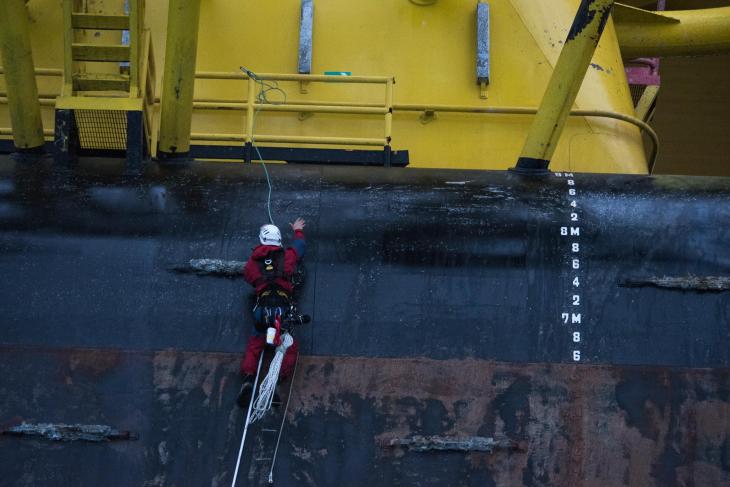 A Greenpeace climbers uses a long lanyard to aid in a final move as they finish climbing the pontoon section of the Polar Pioneer oil rig. © Vincenzo Floramo / Greenpeace